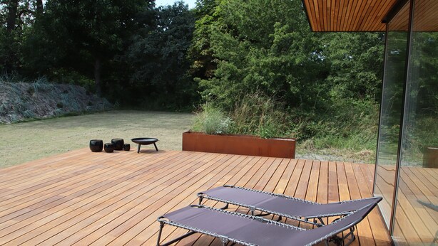 A wooden deck with two lounge chairs, a small table, and a planter. - Holiday home on Bornholm close to sea and beach (Aakirkeby)