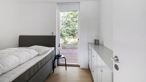 A bedroom with a bed, a desk, and a door leading to an outdoor area. - Holiday home on Bornholm close to sea and beach (Aakirkeby)