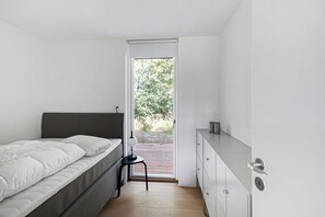A bedroom with a bed, a desk, and a door leading to an outdoor area. - Holiday home on Bornholm close to sea and beach (Aakirkeby)