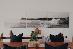 Un coin repas avec une table en bois, des coussins à rayures noires et blanches et une plante servant de décoration centrale.