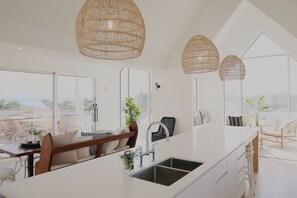 Une cuisine moderne dotée d’un grand îlot central, de meubles blancs et offrant une vue sur la ville.