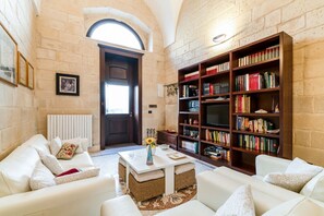 Un saló acollidor amb una llar de foc, una prestatgeria plena de llibres i una zona de seients confortable.