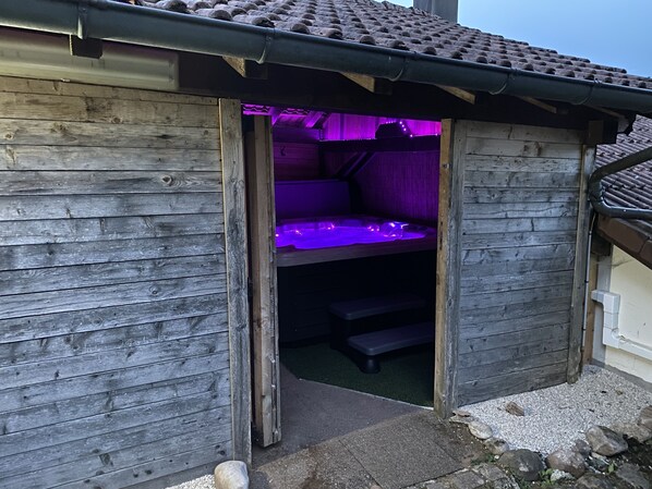 A wooden cabin with a small, enclosed sleeping area illuminated by purple lights.