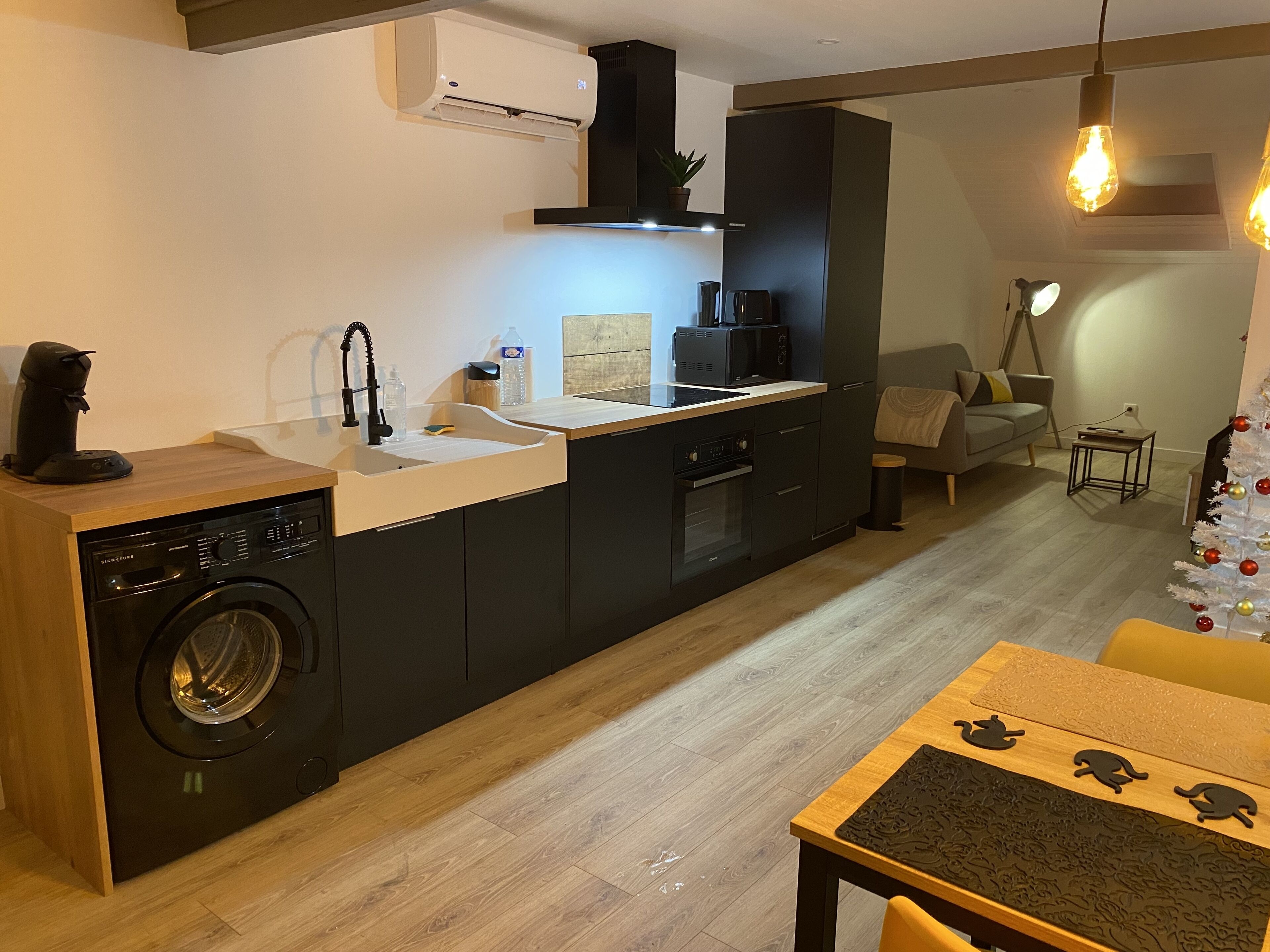 A compact kitchen with a dishwasher, sink, and stove. There is a small dining area with a table and chairs.