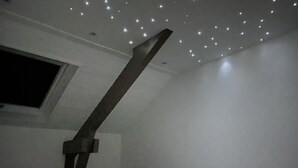 Ein Schlafzimmer mit schrägen Wänden, einem Fenster und einem Bett mit weißer Bettwäsche.