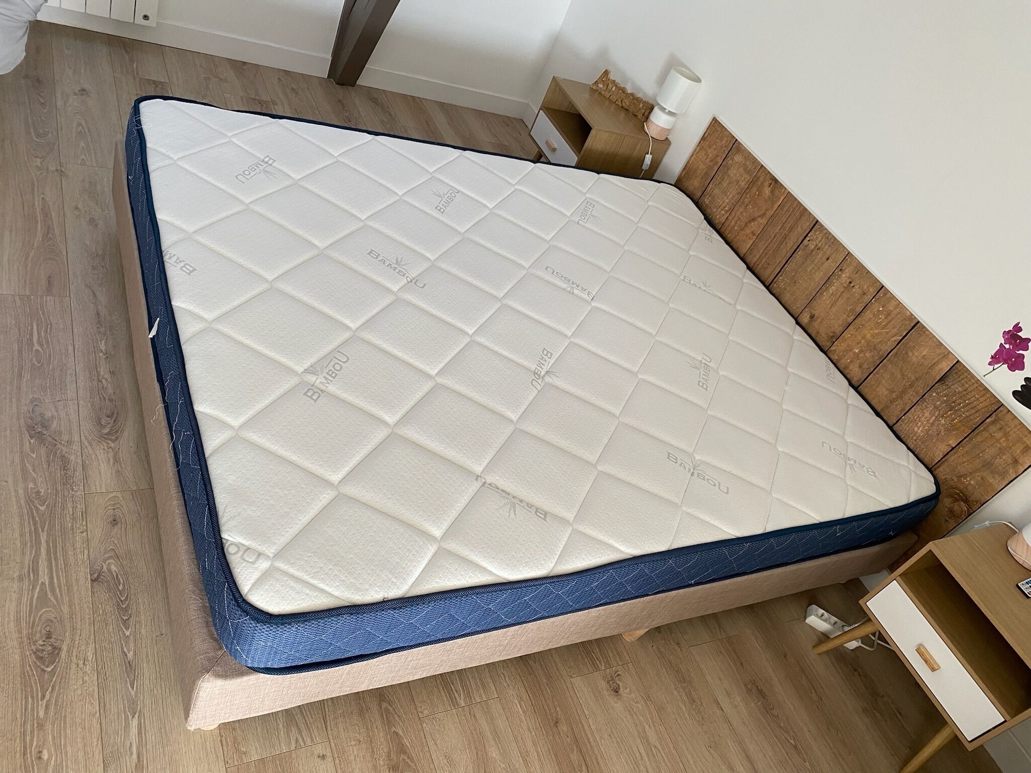 Cama com colchão acolchoado e cabeceira de madeira.