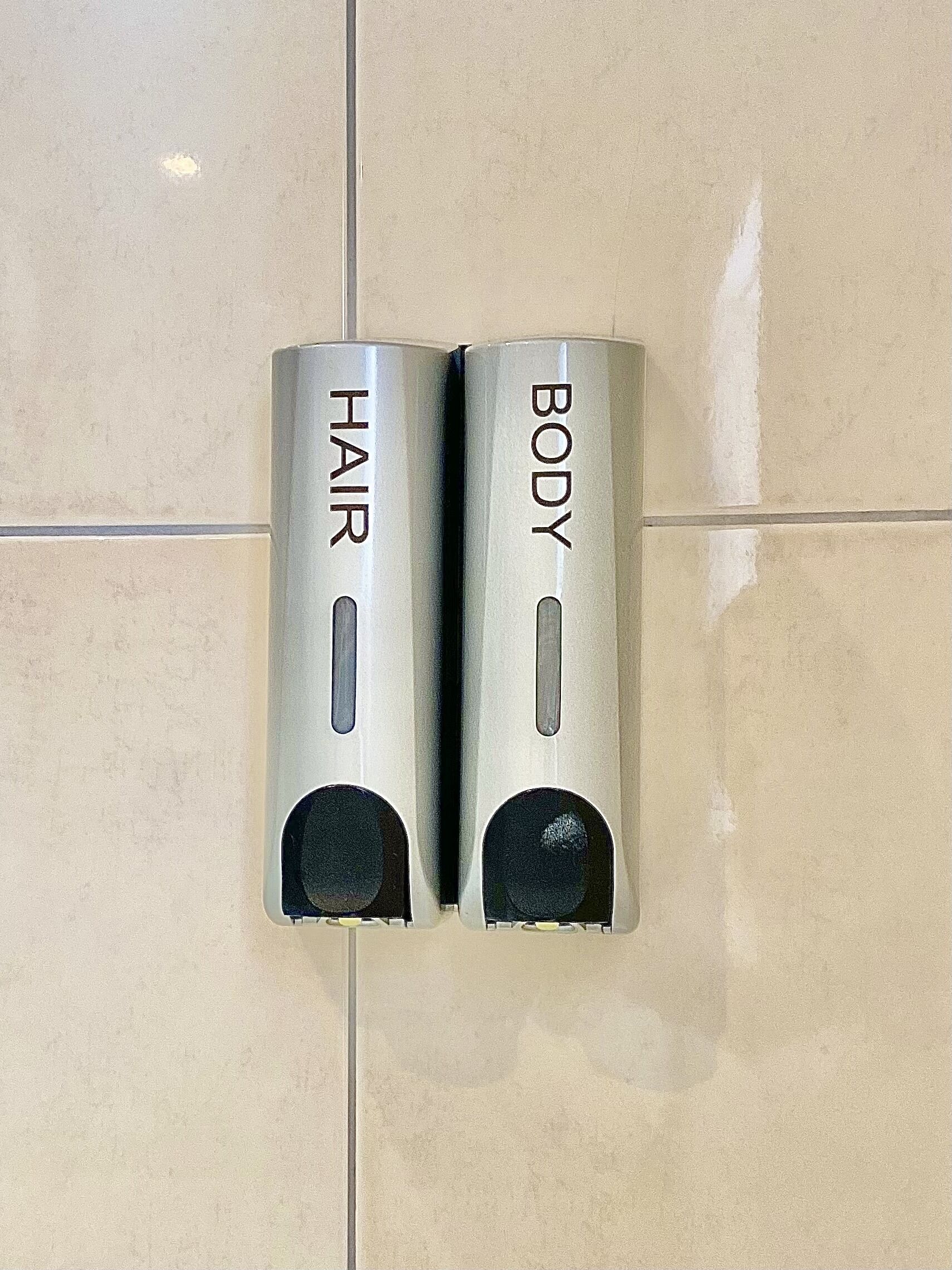 Two wall-mounted hand dryers labeled "HAIR" and "BODY" on a tiled wall.