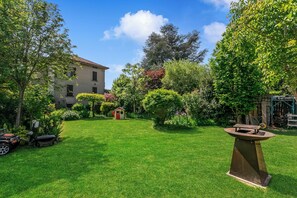 A well-maintained garden with a small shed, a patio table, and a house in the background.