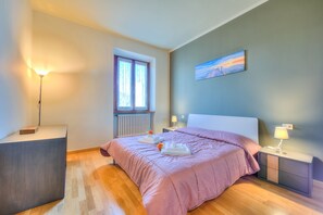 A bedroom with a bed, bedside tables, a window, and a painting on the wall.