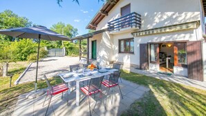 Una casa moderna con patio, zona pranzo all'aperto e area salotto coperta.