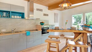 Eine moderne Küche mit grauen Schränken, einer Holz Arbeitsplatte und einer Pendelleuchte.