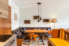 Une cuisine moderne avec une table en bois, une cuisinière intégrée et un coin repas comprenant un banc et des chaises.