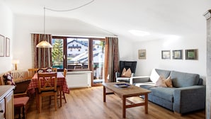 A living room with a sofa, a dining table with chairs, a wooden coffee table, and a window with curtains. - Holiday Apartment "Haus Excelsior Top 40" with Mountain View, Balcony & Wi-Fi (Seefeld in Tirol)