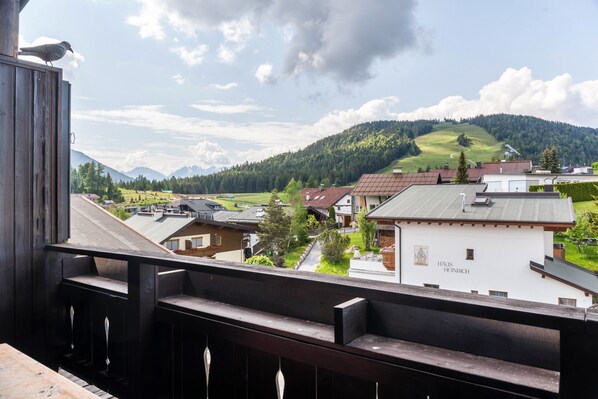 Un balcone con vista su un villaggio, una montagna e un edificio con la scritta 'HAUS HÖHNICH'.
