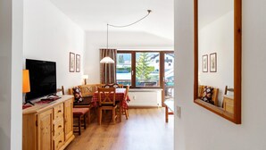 A room with a TV, wooden furniture, a dining table, and a window with a view. - Holiday Apartment "Haus Excelsior Top 40" with Mountain View, Balcony & Wi-Fi (Seefeld in Tirol)