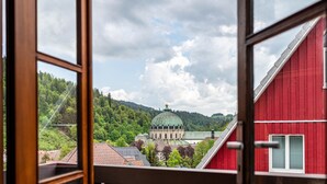 Vista a través de una ventana que muestra un edificio rojo con una estructura en forma de cúpula verde al fondo.