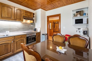 Une cuisine avec des meubles de rangement en bois, une table à manger, des chaises et un four à micro-ondes.