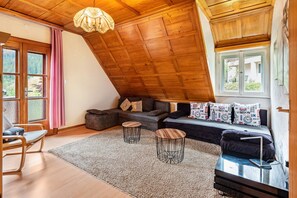 Une pièce de style « loft », avec un plafond en pente, un ensemble de canapés, une petite table et une chaise.
