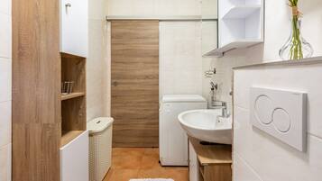 A modern bathroom with a wooden vanity, a white sink, and a shower.