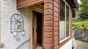 Una casa con fachada de madera, un ventanal grande y una puerta que da al interior.