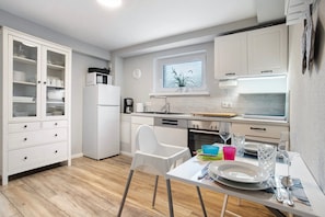 A modern kitchen with white cabinets, a dining table with chairs, and a window with a view.