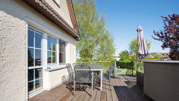 Une terrasse avec une table et des chaises, un espace extérieur couvert et une maison avec une fenêtre.
