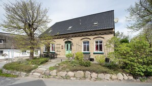 Kaksikerroksinen rakennus, jossa on vihreä ovi, kiviporras ja kivimuuri.