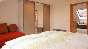 A bedroom with a bed, a red sofa, a wardrobe, and a skylight. - Holiday Apartment "Am Eiberg" with Mountain View, Private Terrace & Wi-Fi (Bad Wildbad)