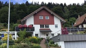 A two-story house with a red and white facade, a visible staircase, and a sign indicating 'Richard-Wagner-Straße'. - Holiday Apartment "Am Eiberg" with Mountain View, Private Terrace & Wi-Fi (Bad Wildbad)