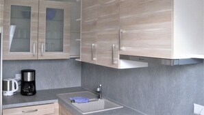A modern kitchen with light wood cabinets, a stainless steel sink, and a coffee maker. - Apartment 'Schelb' with Mountain View, Balcony and Wi-Fi (Sasbachwalden)