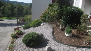 A landscaped garden with gravel paths, various shrubs, and potted plants. - Apartment 'Schelb' with Mountain View, Balcony and Wi-Fi (Sasbachwalden)