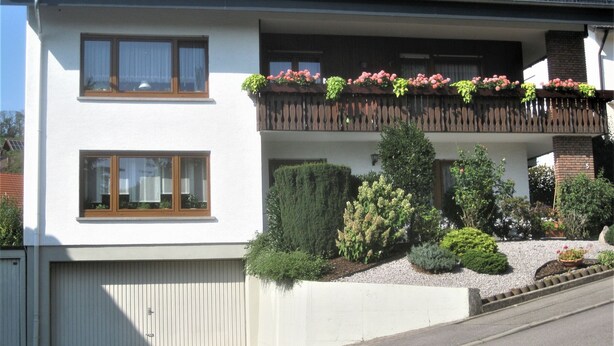 A two-story building with a white facade, a balcony with potted plants, and solar panels on the roof. - Apartment 'Schelb' with Mountain View, Balcony and Wi-Fi (Sasbachwalden)
