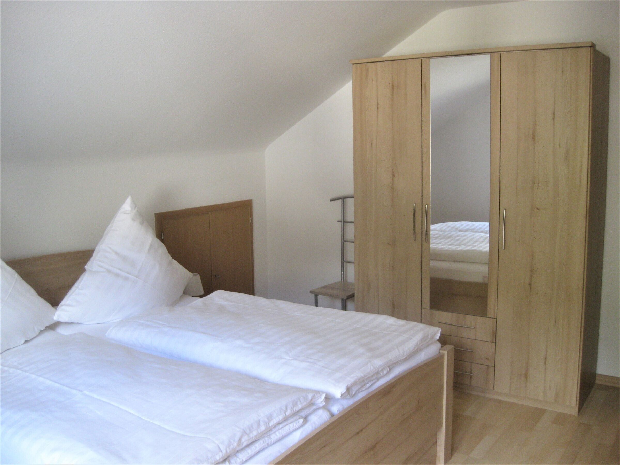 Ein Schlafzimmer mit einem Bett, einem Holzschrank und einem kleinen Nachttisch.