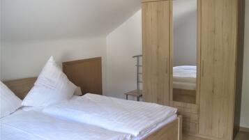 Ein Schlafzimmer mit einem Bett, einem Holzschrank und einem kleinen Nachttisch.