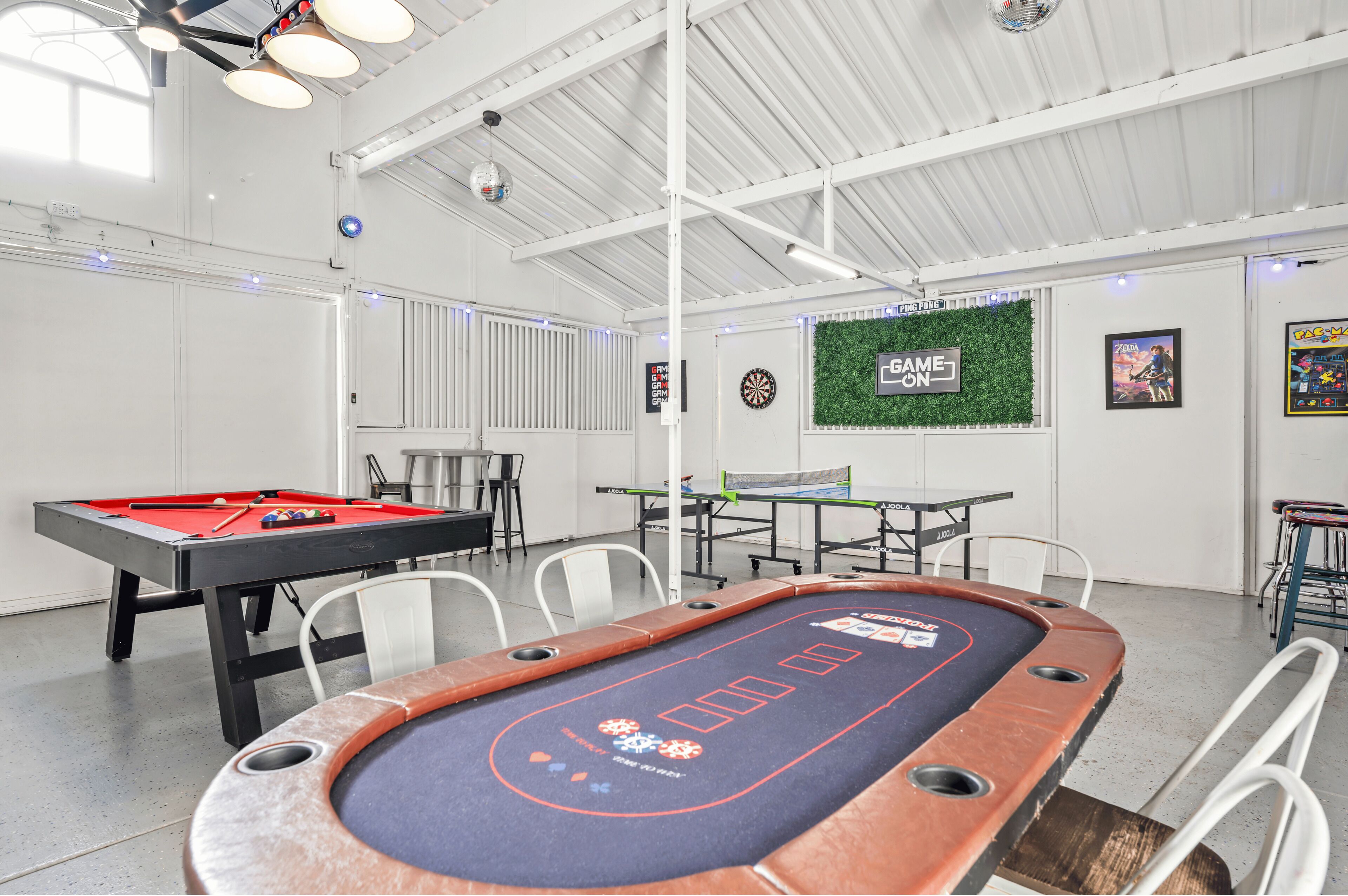 A pool table, dartboard, and a green wall with a 'Game On' sign.