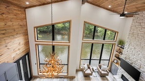 A modern interior with large windows, a fireplace, and a wooden ceiling.