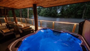 A hot tub with a wooden deck and a view of a river.