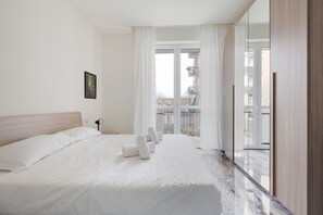 Une chambre d’hôtel avec un grand lit, une table de chevet, une fenêtre avec des rideaux et une vue sur les bâtiments environnants.