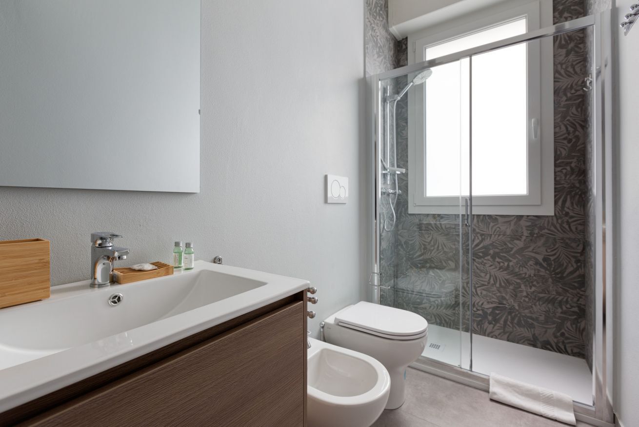 Et badeværelse med stor vask, toilet og brusekabine i glas.