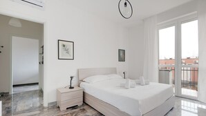 Un dormitorio con una cama grande, una mesita de noche, una lámpara de pared y vistas al exterior.