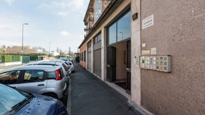 Una fila de coches aparcados junto a un edificio con ventanas amplias y un cartel que indica que la vivienda está a la venta.