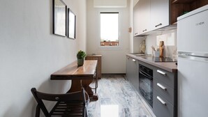 Una cocina con mesa de madera, sillas, ventana, armarios y refrigerador.