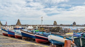 Un puerto con barcos amarrados, un litoral rocoso y un cielo despejado.