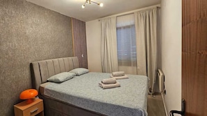 A bedroom with a bed, pillows, a nightstand, a lamp, and a window with curtains. - Apartment Lidija A4 Silo (Silo - island Krk)
