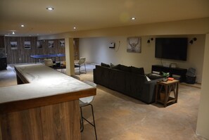 Una sala de estar moderna con un sofá grande, una mesa de centro y un televisor montado en la pared.
