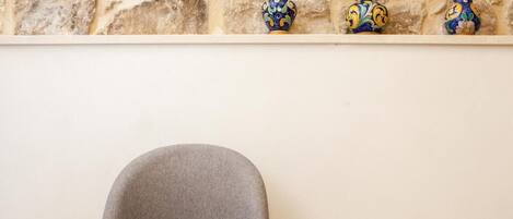 Une chaise adossée à un mur de pierre, avec des vases décoratifs à proximité.