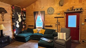 A cozy cabin interior with a wooden interior, a red door, a bookshelf, a fireplace, and a deer head decoration. - Remote and quiet! (English)
