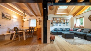 Un interior de madera acogedor con zona de comedor, un sofá y un perro.