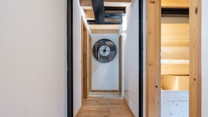 Un pasillo estrecho con suelo de madera y un gran reloj de pared.