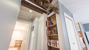 A hallway with a wooden bookshelf, a white door, and a ceiling with exposed beams. - Spacious downtown character rancher (Chilliwack)